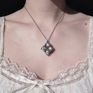 White pearl diamond-shaped pendant on a silver chain necklace